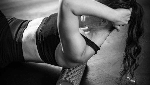Sportswoman Massaging Lower Back with Foam Roller