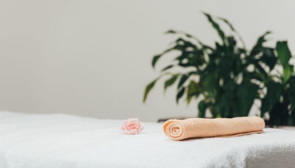 selective focus of massage table with rose and beige towel in spa